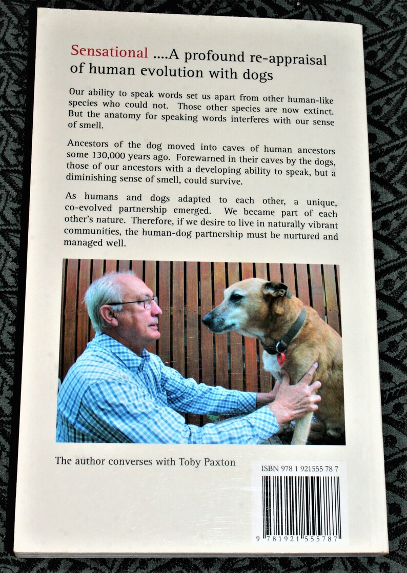 May include: A book cover with a photo of a man and a dog. The book title is "Sensational...A profound re-appraisal of human evolution with dogs". The text on the cover describes the relationship between humans and dogs. The author is Toby Paxton. The ISBN is 978 1 921555 78 7.