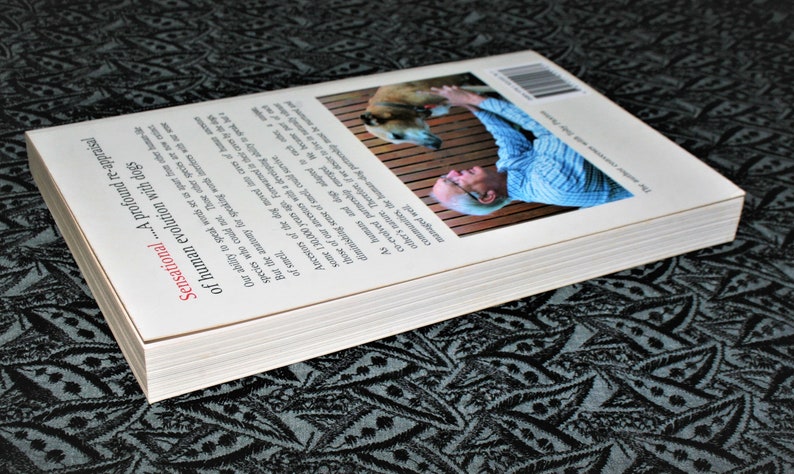 May include: The back cover of a book titled "Sensational...A profound re-appraisal of human evolution with dogs". The cover features a photo of a man petting a dog.