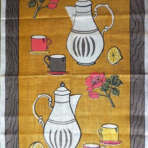 May include: Vintage linen tea towel with a mustard yellow background featuring illustrations of white teapots, cups, lemons, and red roses. The towel has a brown border with a wood grain design. The text "HANDPRINTED" and "ALL LINEN" are visible.