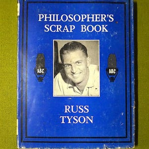 Könnte beinhalten: Ein blaues Vintage-Buch mit dem Titel "Philosopher's Scrap Book" mit einem Schwarz-Weiß-Foto von Russ Tyson. Das Cover zeigt den Text in Weiß und zwei Mikrofon-Illustrationen mit "ABC".