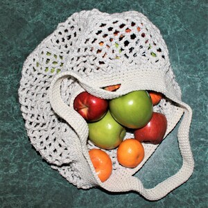 May include: A white crocheted mesh bag filled with red and green apples, and orange mandarins.