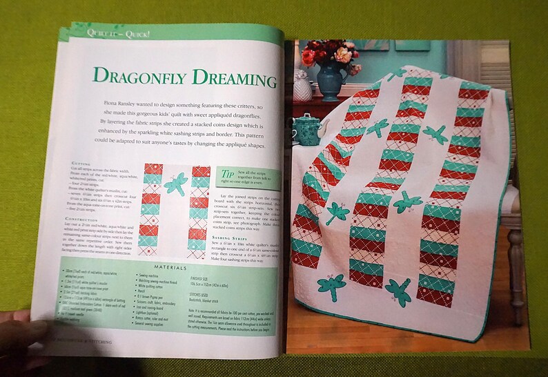 Puede incluir: Una p&aacute;gina de revista con un patr&oacute;n de edred&oacute;n titulado "Dragonfly Dreaming". El dise&ntilde;o del edred&oacute;n incluye rayas blancas, rojas y turquesas con aplicaciones de lib&eacute;lulas. La revista tambi&eacute;n muestra un edred&oacute;n terminado sobre una silla.