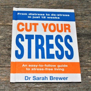 May include: A white book with an orange and blue cover titled "Cut Your Stress". The book cover has the text "From distress to de-stress in just 12 weeks" and "An easy-to-follow guide to stress-free living". The author is listed as "Dr Sarah Brewer".