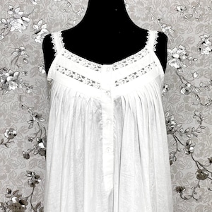 May include: White cotton nightgown with lace trim and button closure. The gown has a gathered skirt and a sleeveless design.