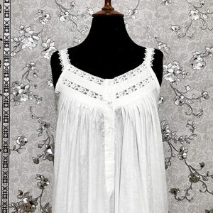 Peut inclure: Une chemise de nuit en coton blanc avec une bordure en dentelle et une fermeture &agrave; boutons. La chemise de nuit est sur un mannequin noir sur un fond &agrave; motifs floraux.