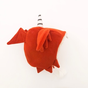 Peut inclure: Un bonnet de dragon en polaire marron avec une corne rayée blanche et noire. Le bonnet est doublé de polaire blanc et a une pointe pointue.