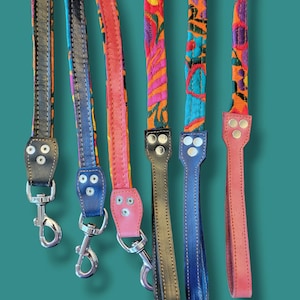 May include: Six dog leashes featuring vibrant, multi-colored embroidered fabric straps paired with solid-colored leather sections. Each leash includes silver-toned metal swivel clips and reinforced rivets securing the leather to the fabric.