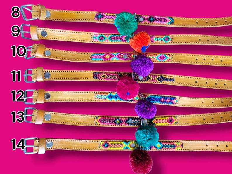 May include: Seven tan leather belts labeled 8 through 14, each featuring a central woven textile strip with colorful geometric patterns. Each belt includes a silver metal buckle and a single hanging yarn pom-pom in various bright colors.