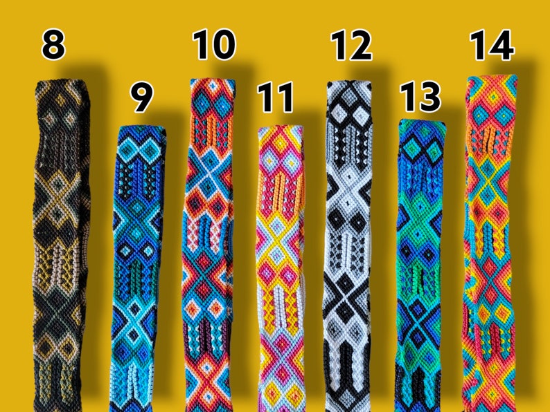 Op de afbeelding: Tien kleurrijke geweven vriendschapsarmbanden met de nummers 8 tot en met 14 gedrukt boven elk armband. De armbanden zijn gemaakt met verschillende kleuren en patronen, waaronder zwart, wit, rood, blauw, groen, geel en oranje.