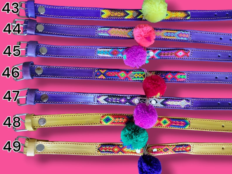May include: Seven leather collars numbered 43 through 49, featuring vibrant woven patterns and colorful pom-poms. Collars 43 through 47 are purple, while 48 and 49 are yellow. Each includes a metal buckle, silver-tone hardware, and stitched edges.