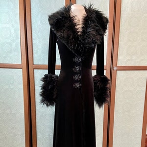 May include: A long black velvet robe with a faux fur collar and cuffs. The robe has a button closure and a lace trim at the hem.