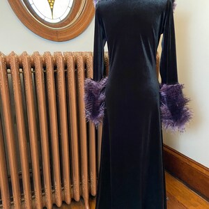 May include: A long black velvet robe with a purple faux fur collar and cuffs. The robe has a long, flowing skirt and a fitted bodice.