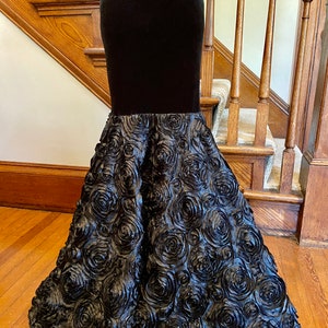 May include: A black velvet skirt with a rose-shaped bottom. The skirt is made of a soft, flowing fabric and has a fitted waist.