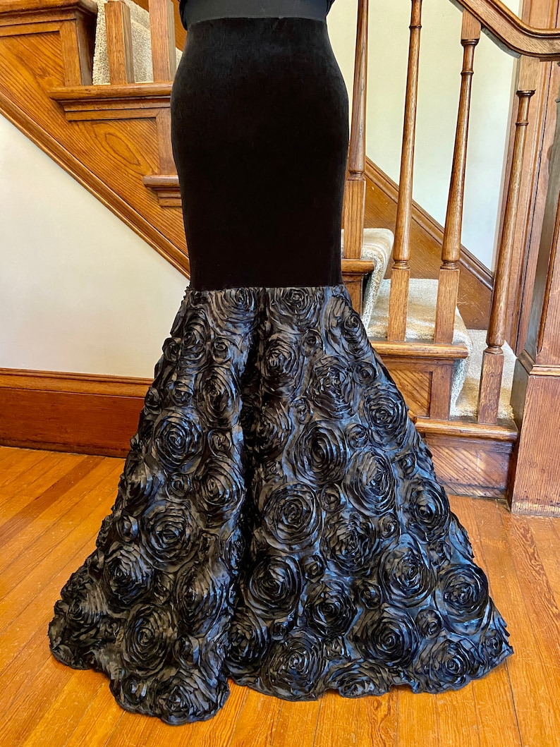 May include: A black velvet skirt with a rose-shaped bottom. The skirt is made of a soft, flowing fabric and has a fitted waist.