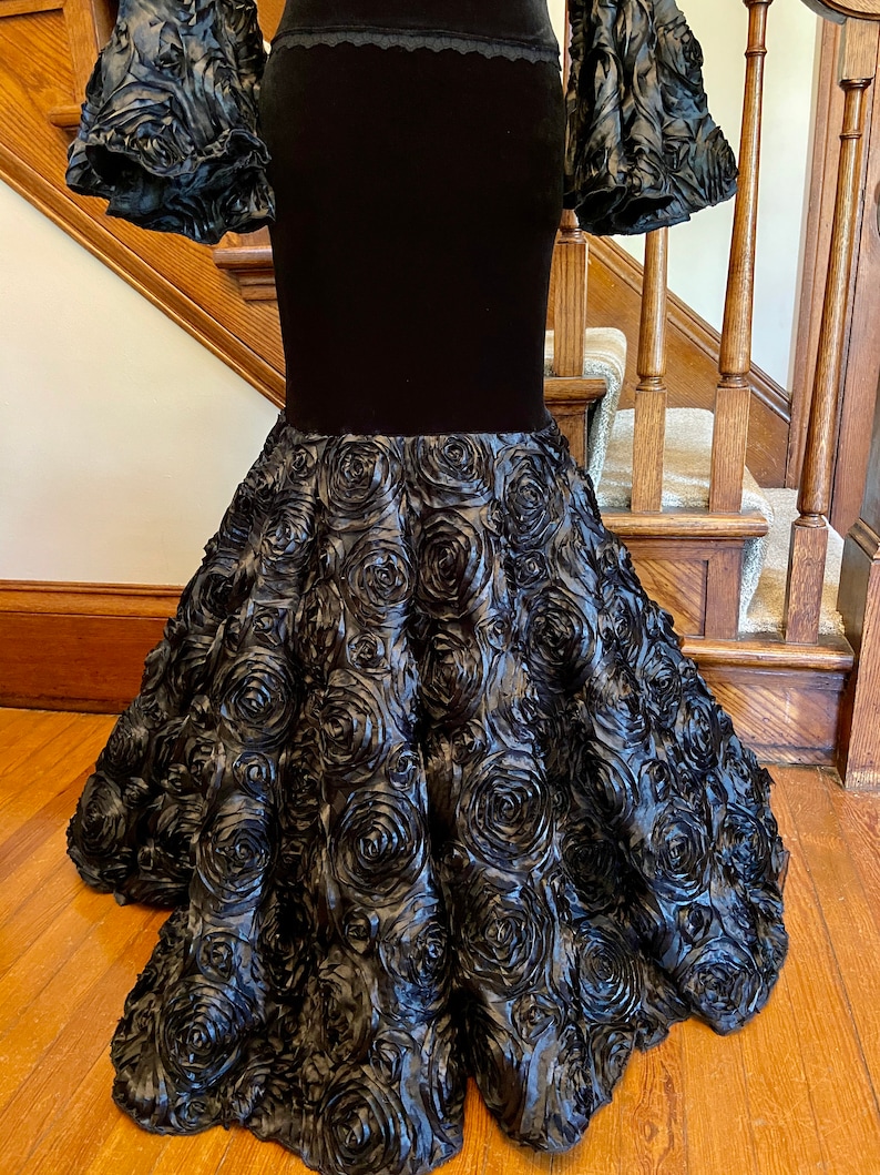 May include: A black velvet skirt with a fitted bodice and a full, ruffled skirt made of black fabric with a rose pattern.