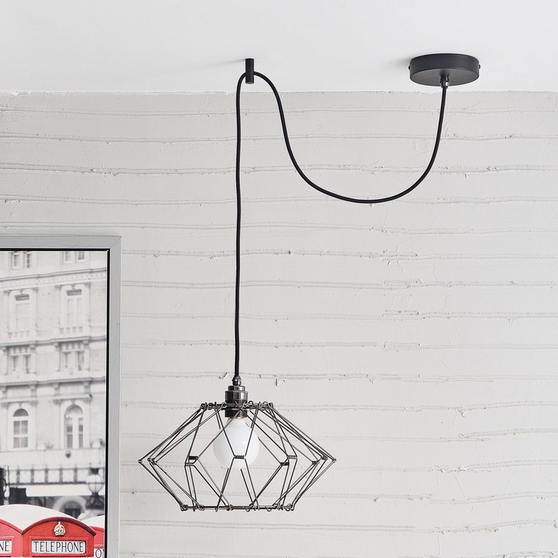 A transformable black wire shade pendant hung and swag to position on a black Easy Hook mounted on a white ceiling.