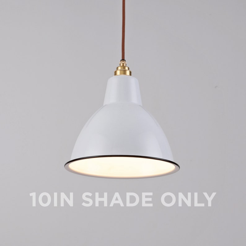 May include: A white pendant light fixture with a 10-inch shade. The light has a glossy finish, a black trim, and a brown cord. The fixture is suspended from the ceiling and has a brass-colored fitting.