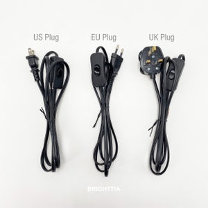 Puede incluir: Tres cables eléctricos negros con interruptores en línea y diferentes tipos de enchufes: EE. UU., UE y Reino Unido.