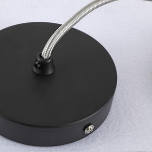 May include: Black ceiling rose with a silver braided cord attached. The rose has two screws visible.