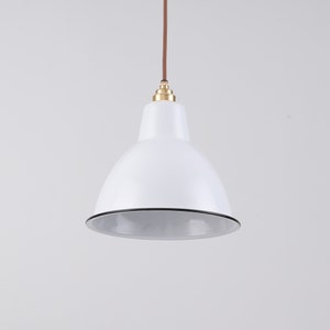 May include: White pendant light with a rounded shade and a black trim. The light fixture hangs from a brown cord and features a brass-colored fitting. The design is simple and modern, suitable for various interior styles.