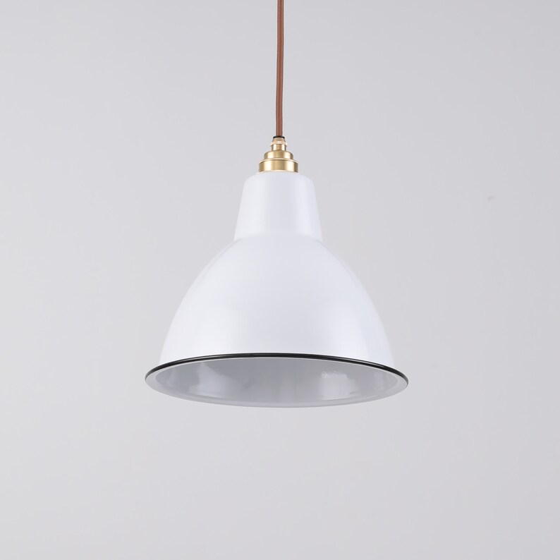 May include: White pendant light with a rounded shade and a black trim. The light fixture hangs from a brown cord and features a brass-colored fitting. The design is simple and modern, suitable for various interior styles.