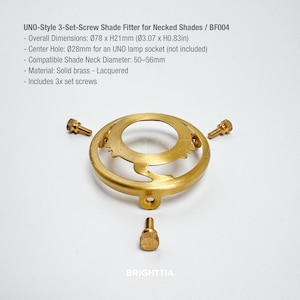 May include: A brass UNO-style 3-set-screw shade fitter for necked shades. Overall dimensions are 3.07 inches in diameter and 0.83 inches high. Includes three set screws. The text "BRIGHTTIA" is at the bottom.