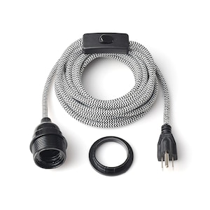 Puede incluir: Cable eléctrico cubierto de tela blanco y negro con un interruptor en línea negro, un enchufe negro, un casquillo negro y una roseta de techo negra.