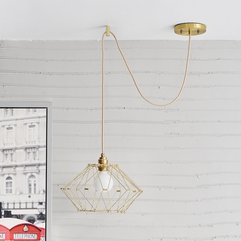 A transformable gold wire shade pendant hung and swag to position on a gold Easy Hook mounted on a white ceiling.