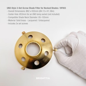 May include: A brass UNO-style 3-set-screw shade fitter for necked shades. Overall dimensions are 062mm x H35mm (Ø4.13 x H1.38in). The center hole is Ø33mm. Compatible with shade neck diameters of 85-105mm. Includes 3 set screws.