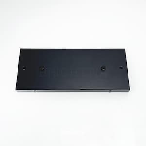 May include: A rectangular black metal plate with rounded corners. The word "BRIGHTTIA" is subtly printed across the center. There are four small holes and two screws visible on the surface. The plate is set against a white background.