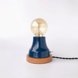 May include: A blue ceramic table lamp with a wooden base and a clear glass light bulb.
