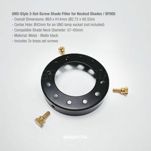 May include: A matte black UNO-style 3-set-screw shade fitter for necked shades. The overall dimensions are Ø2.72 x H0.55 inches. Includes three brass set screws. The center hole is Ø42mm for an UNO lamp socket.