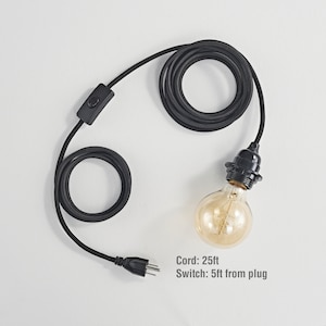 May include: Black electrical cord with a black inline switch and a black plug. The cord is 25 feet long with the switch located 5 feet from the plug. The cord is attached to a black light socket with a clear glass light bulb.