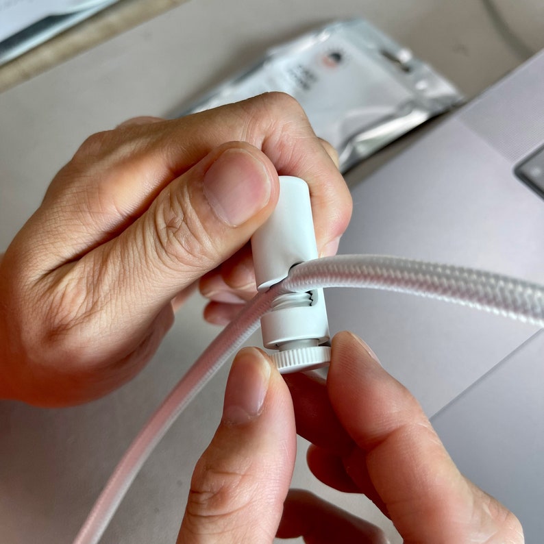 Hand holding and tightening white fabric cord onto white Easy Hook slot.