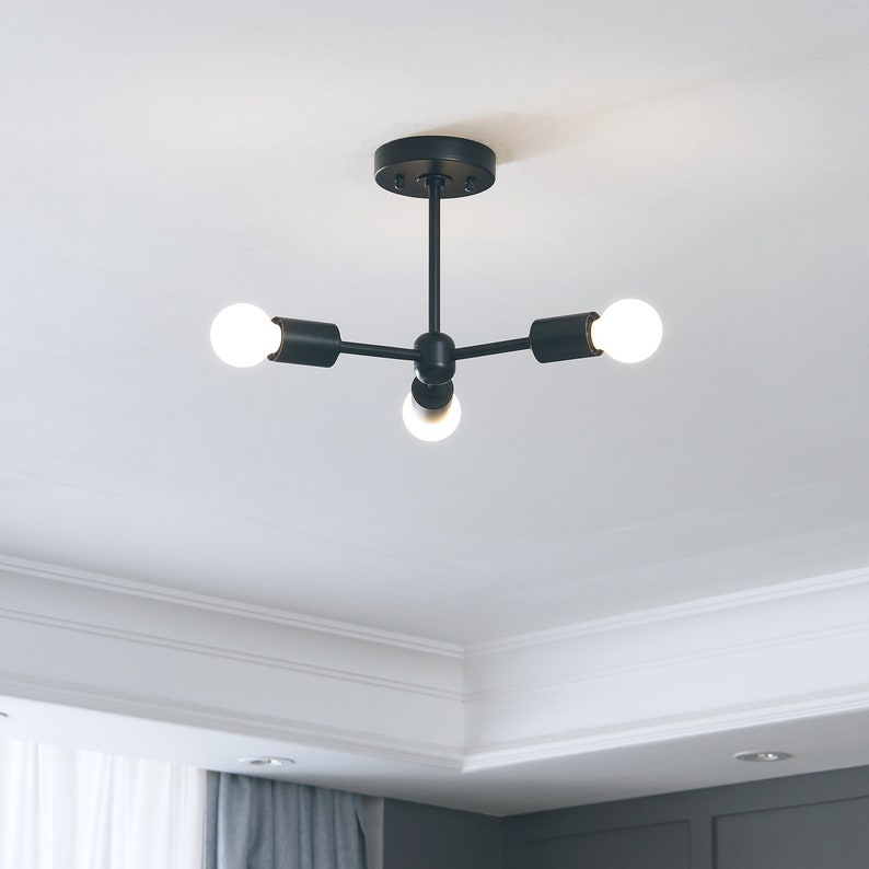 3-Light Semi Flush Ceiling Light - Matte Black - Industrial Modern Minimalist Sputnik Chandelier Lighting - Mid Century Exposed Bulb Lamp - Image showing ceiling lamp mounted on ceiling with lights on in living room interior - Brighttia.etsy.com