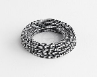May include: A roll of black and white chevron patterned electrical cord. The cord is coiled into a circle and is ready to be used for a variety of electrical projects.