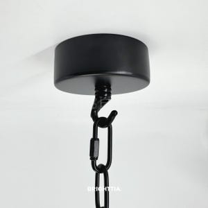 May include: A black ceiling rose with a matching hook and chain. The chain is connected to the rose with a black hook. The word "BRIGHTTIA" is printed on the chain.
