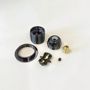 May include: A set of black electrical components for a light fixture. The set includes a ceiling rose, a lamp holder, a connector, a screw, and a brass terminal.