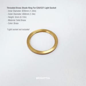 Op de afbeelding: Een messing lampenkapring voor E26/E27 fittingen. De ring heeft een binnendiameter van 39 mm, een buitendiameter van 48 mm en een hoogte van 3 mm. Het materiaal is massief messing. De tekst op de afbeelding luidt "Threaded Brass Shade Ring For E26/E27 Light Socket".