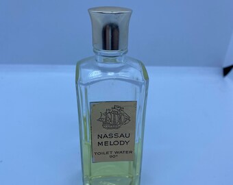 May include: A clear glass bottle of Nassau Melody toilet water with a silver cap. The label is yellow with black text and a ship illustration.