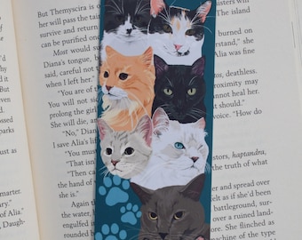 Op de afbeelding: Een tealblauwe bladwijzer met een kleurrijke illustratie van zes katten. De katten zijn gestapeld, met hun koppen en schouders zichtbaar. De katten zijn allemaal in verschillende kleuren en patronen, waaronder zwart, wit, oranje en driekleurig. De bladwijzer heeft een pootprintpatroon op de achtergrond.