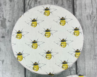 May include: Three reusable food wraps with a white background and a repeating pattern of yellow and black bees. The wraps are in different sizes.