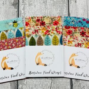 May include: Three sets of beeswax food wraps with different floral patterns. Each set includes three wraps and comes with a card featuring a fox illustration and the text "The Little Fox Workshop" and "Beeswax Food Wraps".