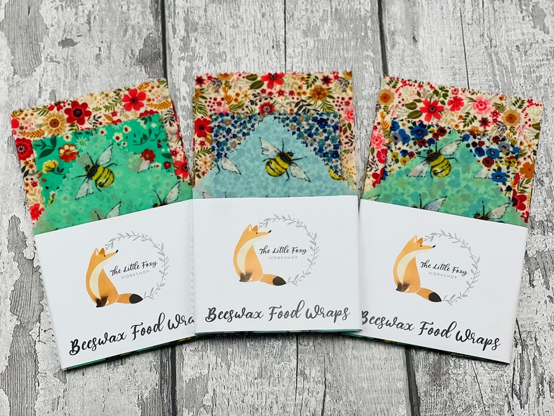 May include: Three sets of beeswax food wraps with floral and bee designs. Each set is packaged in a white card with a fox logo and the text "The Little Foxy Workshop" and "Beeswax Food Wraps".