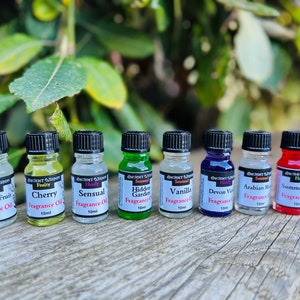 May include: Ten small glass bottles with black caps, each containing a different coloured liquid. The bottles are labelled with the names of different scents, such as "Passion Fruit", "Cherry", "Sensual", "Hidden Garden", "Vanilla", "Devon Violet", "Arabian Musk", and "Summer Bloom".
