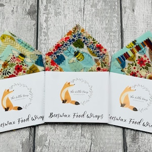 May include: Three packages of beeswax food wraps with a floral and bee design. Each package has a white label with a fox illustration and the text "The Little Foxy Workshop" and "Beeswax Food Wraps".
