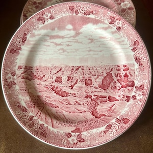 May include: A set of vintage plates with a red and white design. The plates feature a detailed illustration of the Grand Canyon, with the text "GRAND CANYON FROM POINT SUBLIME". The rims are decorated with floral patterns.