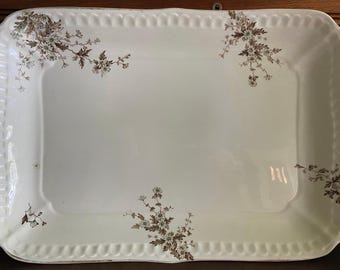 May include: A white rectangular serving platter with a scalloped edge and a floral design in brown and white.