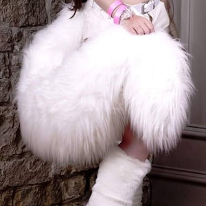 Puede incluir: Botas blancas de pelo con diseño de pata y garras. Las botas son de tacón alto y tienen un pelo blanco y esponjoso que cubre toda la bota.