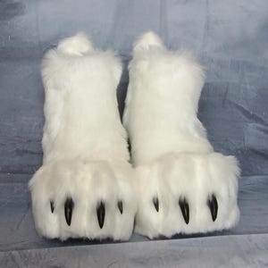 Puede incluir: Un par de botas blancas y peludas con grandes pies en forma de pata. Las botas tienen garras negras y est&aacute;n hechas de un material suave y afelpado. Las botas est&aacute;n dise&ntilde;adas para parecerse a patas de animales.